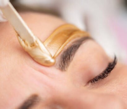 Applying Gold Colored Wax with Spatula on Woman's Face